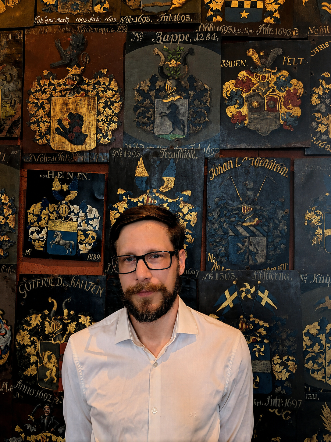 Tommie Rappe Petersson framför adliga ätten Rappes introduktionsplåt i Riddarhuset.